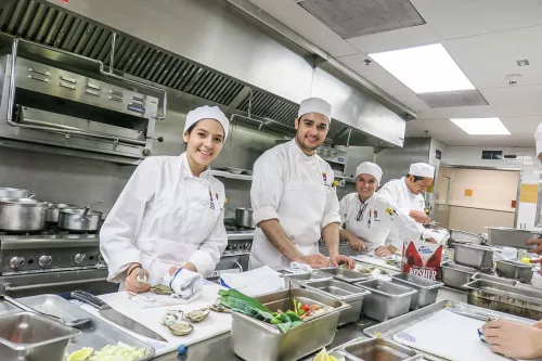 Students smile while working in an ICE culinary school in Los Angeles kitchen