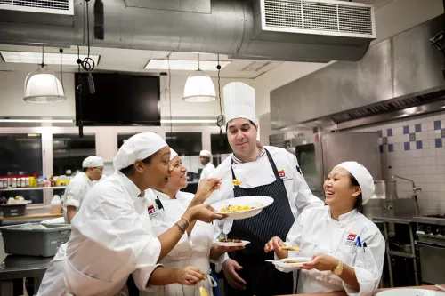 Students and chef instructors taste dishes in ICE's culinary arts campus programs.