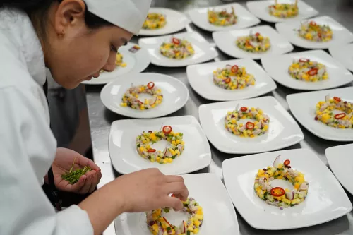 Student plating a dish in a professional kitchen in culinary school in Los Angeles