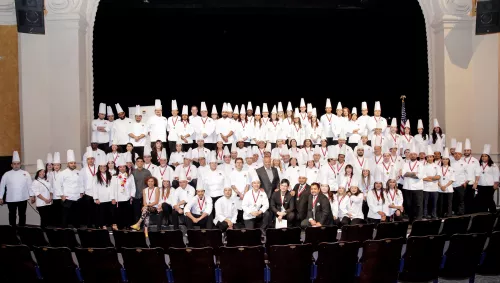 Wolfgang Puck poses with the Los Angeles campus' 2018-2019 graduates.