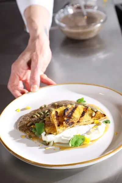 a chef pushes forward a plate of yogurt, grilled pineapple and chia pudding from ICE's Culinary Nutrition course