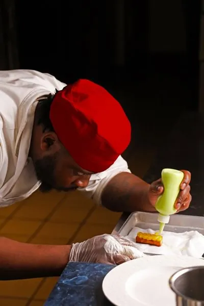 an Advanced Contemporary Cuisine & Technique student uses a squeeze bottle to finish a dish
