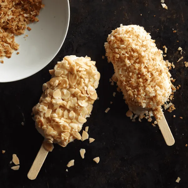 almond and coconut popsicles against a black background