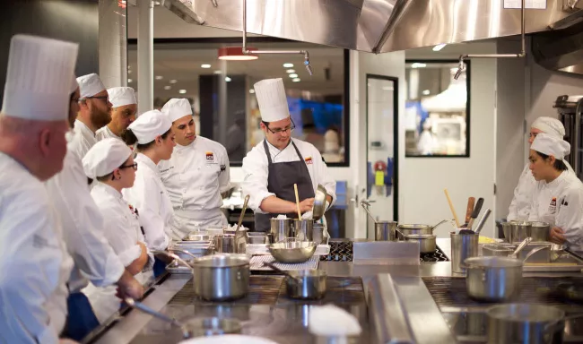 An ICE Chef Instructor demonstrates omelette technique in class to culinary school students