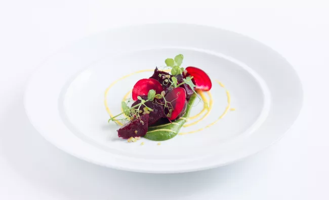 Red beets and green herbs plated on a white dish
