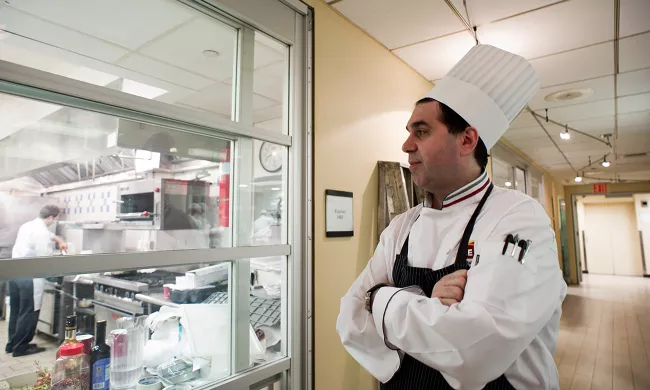 An ICE chef instructor peers into a kitchen classroom at the Institute of Culinary Education
