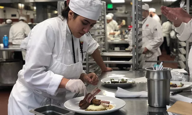 A Culinary Arts student plates meat