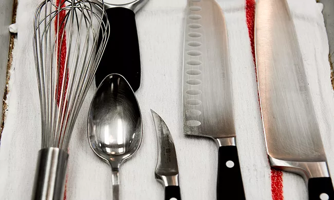 A set of tools, including a whisk, tasting spoon and various knives, that students use in culinary arts campus programs.