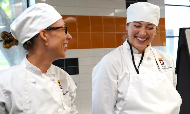 Two students in chef whites smile