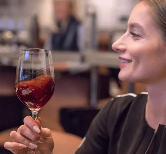 Student evaluating the quality of a glass of red wine