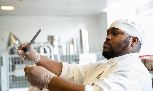 A culinary arts student hones his knife in class at the Institute of Culinary Education