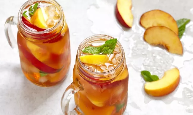 Glasses filled with brown drinks, garnished with peach slices