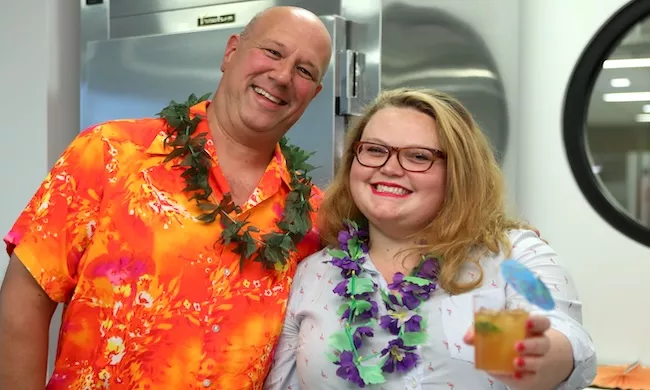 Two people smile while holding a tiki cocktail
