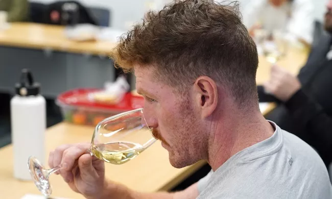 A student smells a glass of white wine