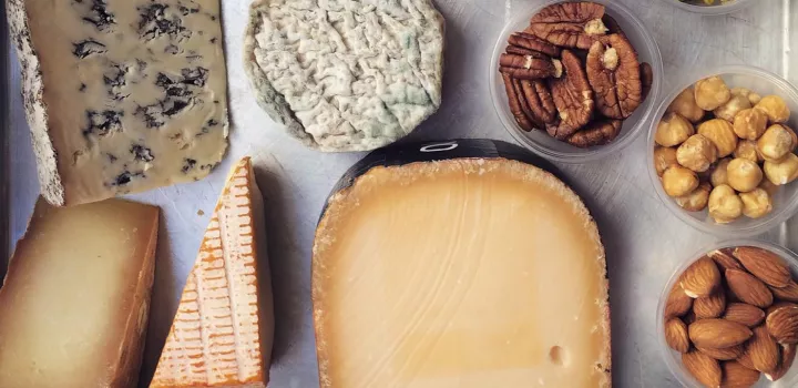 An assortment of cheeses on a cheese board with nuts