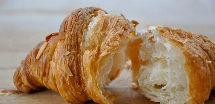 A croissant is cut in half on top of a wooden board