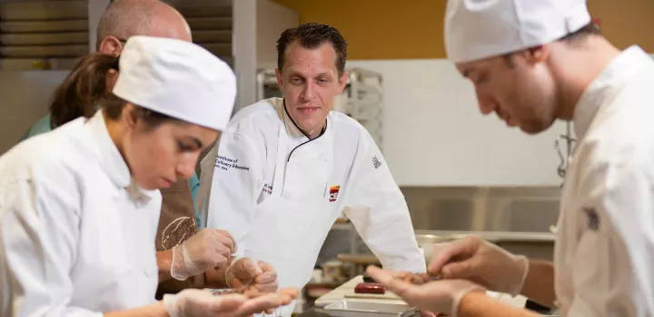 chef michael laiskonis looking as culinary students prepare a dish