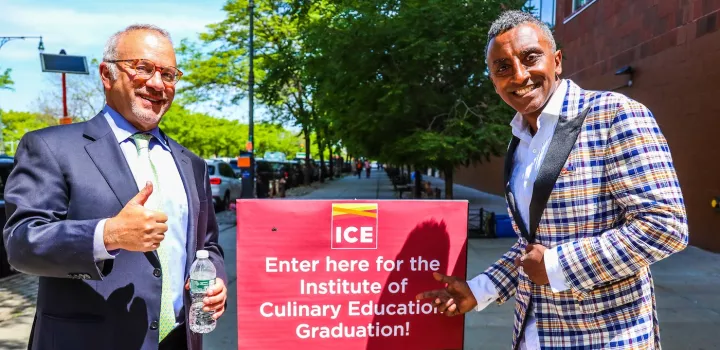 ICE President and CEO Rick Smilow and ICE commencement speaker Chef Marcus Samuelsson stand in front of a sign that says "Enter here for the Institute of Culinary Education Graduation"