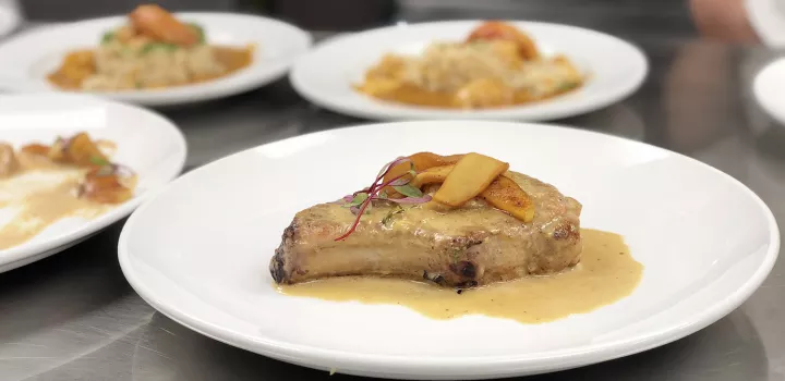 Chef-Instructor Mette Williams makes pork chop with with calvados apples with Culinary Arts students.