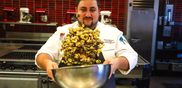 Lead Chef & Operations Manager Joshua Resnick tosses roasted cauliflower in a metal bowl