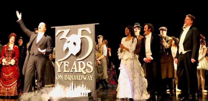 The Broadway cast of The Phantom of the Opera stands next to Chef Jürgen David's 35th anniversary cake