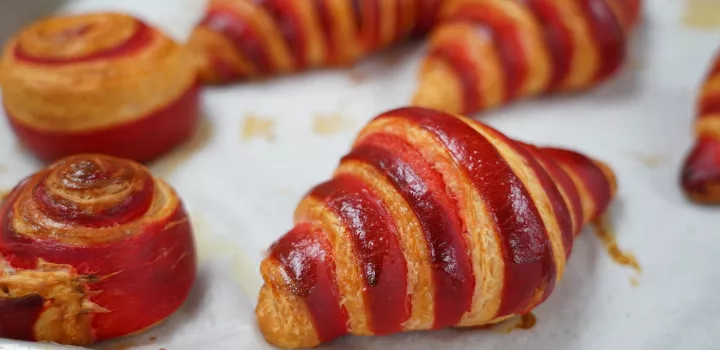 A red-striped croissant sits on a piece of white parchment paper