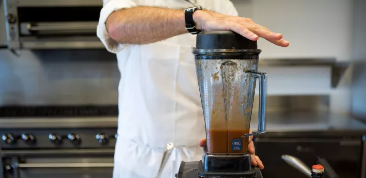 Chef holding blender closed while pureeing tomato soup
