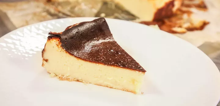 A piece of Basque-style cheesecake on a white plate made using Chef Eric's Basque cheesecake recipe