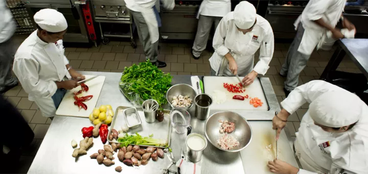 busy professional kitchen where chefs are preparing mise en place for dinner service