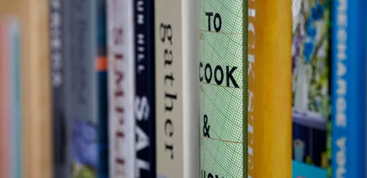 A stack of cookbooks on a shelf