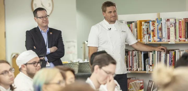 Chef Lachlan listens while Chef Curtis Stone is introduced for a guest lecture.