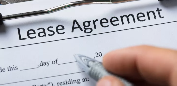 A hand is beginning to fill out a lease agreement.