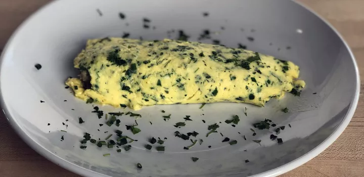 A French omelet garnished with fresh herbs.