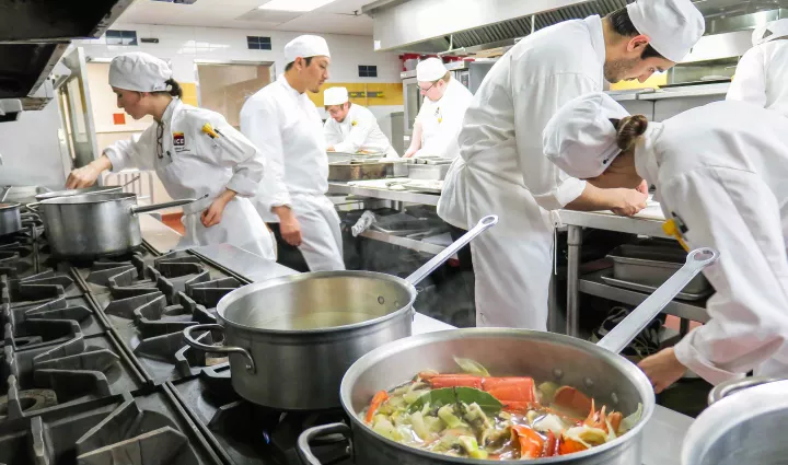 Culinary school students work in the background of pots simmering on a stove at ICE