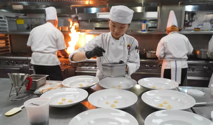 An ICE student plates multiple dishes as part of ICE's culinary career training program