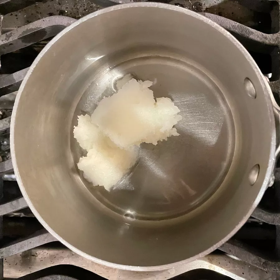 Coconut oil, a butter alternative, melts in a stainless steel pot